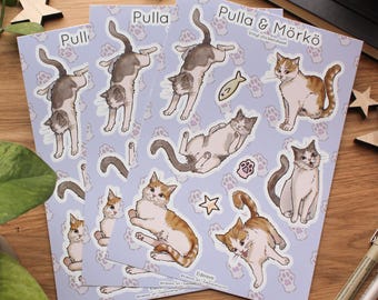 May include: Three sheets of vinyl stickers with cat illustrations in different poses. The stickers have a pale purple background with paw prints and star shapes. The text "Pulla & Mörkö" is printed on one sheet.