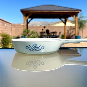 May include: A white ceramic mug with a black handle and the text "But First, Coffee" in a black, bold font. The mug is on a white surface.