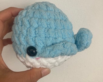 May include: A crocheted blue and white dolphin plush toy with a black button eye.