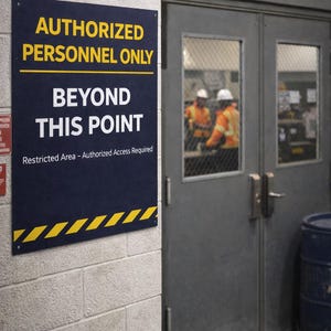 May include: A navy blue sign on a brick wall reads "AUTHORIZED PERSONNEL ONLY BEYOND THIS POINT". The sign has yellow and white text and a yellow diagonal stripe design. A gray door is to the right.