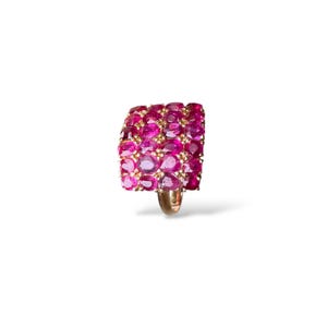 May include: A gold ring with a rectangular face densely packed with oval-cut, bright pink gemstones. The gemstones are set closely together, forming a textured surface. The ring has a simple, polished gold band.