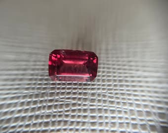 Op de afbeelding: Een diep roze edelsteen met een rechthoekige snede en een gladde, gepolijste afwerking.