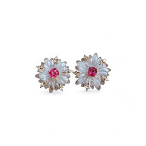 May include: A pair of gold earrings with a flower design. Each earring features a pink gemstone in the center surrounded by clear stones.