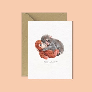 May include: A greeting card featuring a watercolour illustration of two monkeys in an embrace. One monkey is brown, the other is grey. The text "Happy Mother's Day" is printed below the image. The card is in a brown envelope.