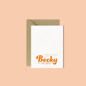 Op de afbeelding: Een witte kaart met de oranje tekst "Portraits by Becky" en een kraft papieren envelop. De kaart toont ook de woorden "Pets &bull; People &bull; Wildlife Artist" in kleinere letters, met een perzikkleurige achtergrond.