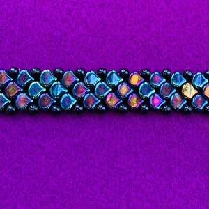 May include: A black and iridescent beaded bracelet with a silver clasp. The beads are arranged in a chevron pattern.