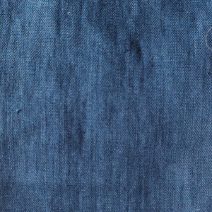 May include: Close-up of a dark blue denim fabric with a textured weave.
