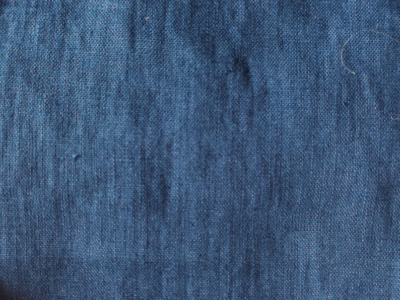 May include: Close-up of a dark blue denim fabric with a textured weave.