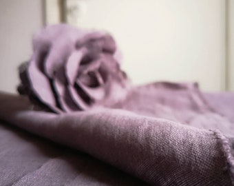 May include: A soft, mauve-colored linen fabric draped over a surface. The fabric is folded and textured, creating a soft and inviting look.