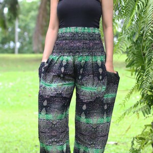 May include: A woman wearing a black tank top and green and black patterned pants with a paisley design. The pants have an elastic waistband and pockets.