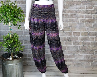 May include: Black and purple printed pants with a wide elastic waistband. The pants are loose fitting and have a wide leg. The pants are being modeled on a white mannequin against a brick wall.