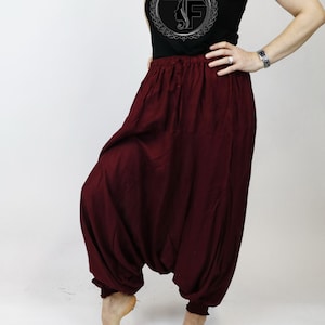 May include: A pair of maroon-colored, loose-fitting pants with an elastic waistband. The pants are gathered at the ankles and have a flowing, comfortable look.