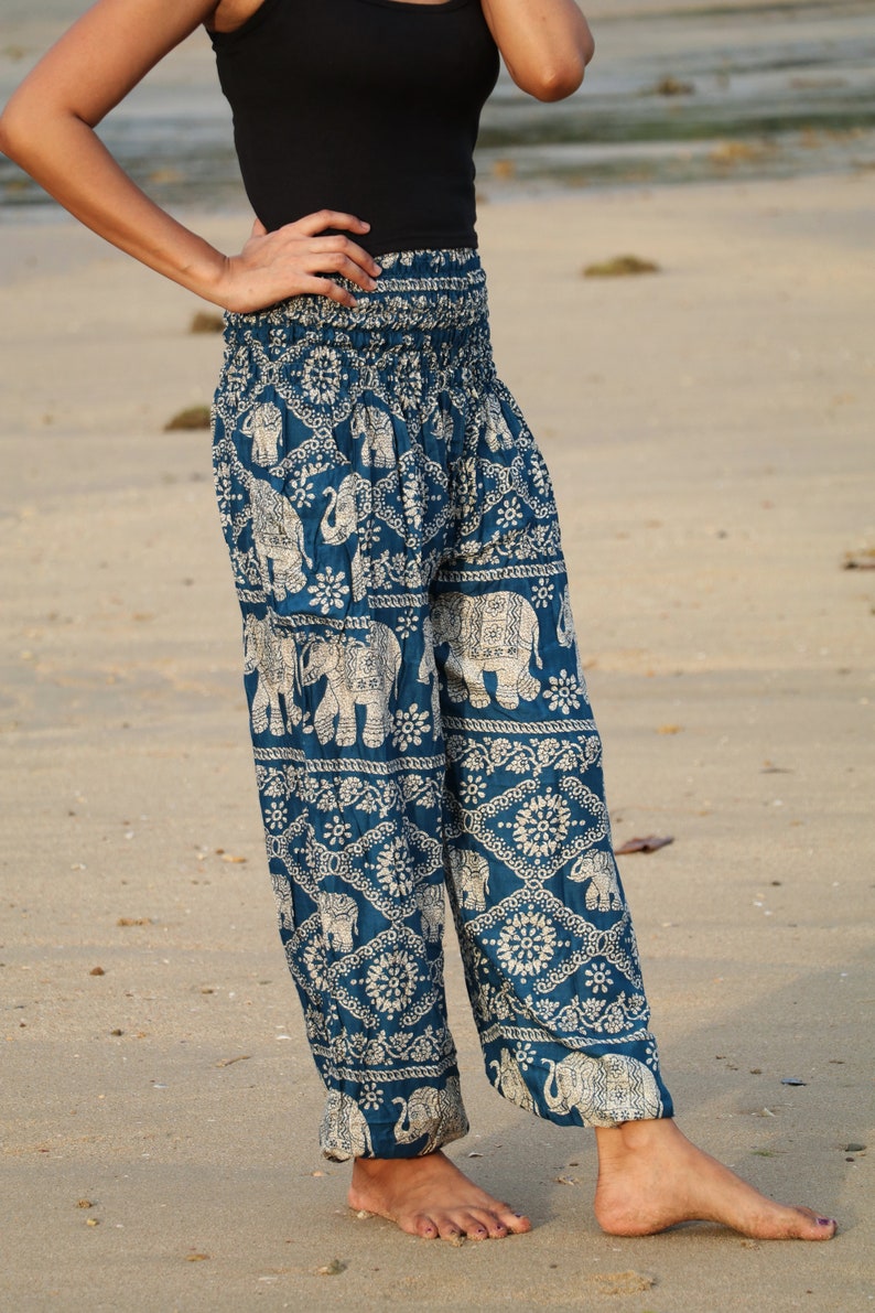 May include: A pair of blue harem pants with a white elephant print. The pants have a wide, flowing leg and a comfortable elastic waistband.