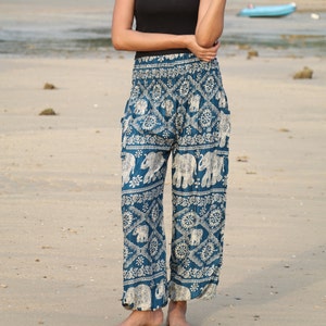 May include: Teal blue pants with a white elephant print. The pants have a wide leg and an elastic waistband.