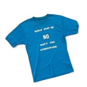 May include: A bright blue short-sleeved t-shirt featuring white text printed on the front that reads: WHAT PART OF NO DON T YOU UNDERSTAND. The shirt has a crew neckline and a standard fit, showcasing a bold graphic design on the chest area.