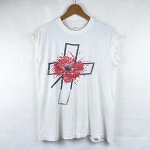 Puede incluir: Camiseta blanca sin mangas con un contorno negro de una cruz y un gráfico de flor de amapola roja.