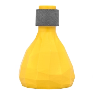 May include: A bright yellow, faceted, geometric-shaped object with a wide base that tapers toward a narrow neck. A dark gray, textured, cylindrical band is positioned around the upper neck section of the yellow structure.