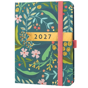 Könnte beinhalten: Ein türkisfarbener Hardcover-Planer mit einem botanischen Muster aus rosa, gelben und grünen Blättern und Blumen. Ein horizontales goldenes Band in der Mitte zeigt das Jahr 2027 in schwarzer Schrift. Ein vertikales rosa Gummiband hält den Planer geschlossen.