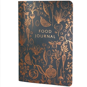 May include: A dark grey food journal with a copper-coloured line art pattern featuring various vegetables, fruits, and bees. The text FOOD JOURNAL is printed in the centre in a matching copper-coloured font against the dark textured background.