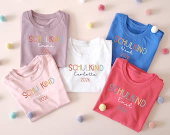 Schulkind T-Shirt zur Einschulung mit Name & Jahreszahl in 12 verschiedenen Farben für das Schulkind 2026 für Jungs u. Mädchen