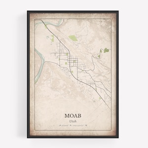 May include: Framed map print of Moab, Utah, featuring a detailed topographical view with roads, rivers, and green areas. The print has a vintage aesthetic with the city name and coordinates at the bottom. The frame is black.