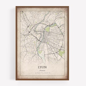 May include: A framed map of Lyon, France, with a vintage design. The map shows the city's street layout in black lines, with green areas for parks and rivers. The city name and coordinates are printed at the bottom of the map.