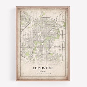 Puede incluir: Una impresión enmarcada del mapa de Edmonton, Alberta, con un diseño detallado de las calles en negro y verde sobre un fondo de estilo vintage. El nombre de la ciudad y las coordenadas están impresos en la parte inferior. El marco es de color marrón claro.