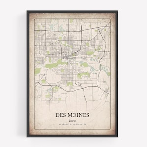 May include: A framed map print of Des Moines, Iowa, with a vintage aesthetic. The map features a detailed street grid, green areas, and the city's name and coordinates at the bottom. The frame is black.
