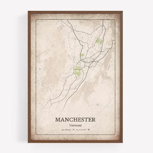 Könnte beinhalten: Gerahmter Karten-Druck von Manchester, Vermont, mit einem detaillierten Straßennetz und grün schattierten Bereichen. Die Karte hat eine Vintage-Ästhetik mit dem Stadtnamen und den Koordinaten in einer klassischen Schriftart. Der Rahmen ist dunkelbraun.