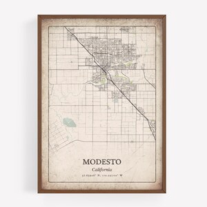 May include: A framed map print of Modesto, California, in a vintage style. The map features a detailed street grid, waterways, and the city's name and coordinates. The frame is a dark brown color.
