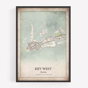 May include: A framed map print of Key West, Florida, in a vintage style. The map features a detailed layout of the island, with streets, waterways, and green areas. The text "KEY WEST Florida" is displayed at the bottom, along with coordinates.