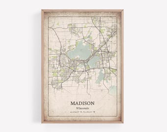 May include: Framed map print of Madison, Wisconsin, featuring a detailed street layout with green and blue areas representing parks and lakes. The map has a vintage aesthetic with the city name and coordinates at the bottom.