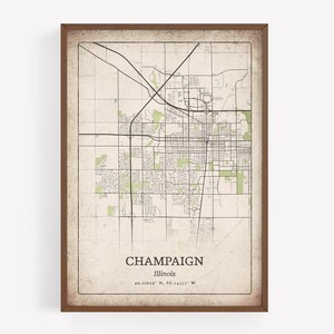 May include: A framed map print of Champaign, Illinois, featuring a detailed street layout in black lines against a beige background. The city name and coordinates are printed at the bottom. The frame is a dark brown color.