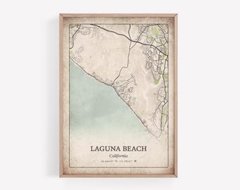May include: Framed map print of Laguna Beach, California, with a vintage aesthetic. The map features the city's layout, coastline, and surrounding areas in neutral tones, with a light blue ocean and green accents. The text "LAGUNA BEACH" is displayed prominently.