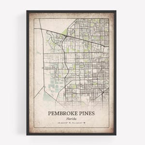 May include: Framed map print of Pembroke Pines, Florida, showing a detailed street layout in black lines on a vintage-style beige background. The city name and coordinates are printed at the bottom. The map is enclosed in a black frame.