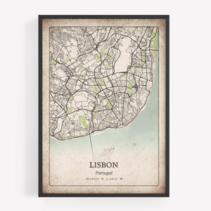 May include: Framed map print of Lisbon, Portugal, in a vintage style. The map features a detailed street layout with green areas and a light blue water area. The city name and coordinates are printed at the bottom.