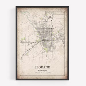 May include: Framed map print of Spokane, Washington, in a vintage style. The map features a detailed street layout with green and beige tones, and the city's name and coordinates are printed at the bottom.