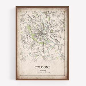 Puede incluir: Impresión enmarcada de un mapa de Colonia, Alemania, con un plano detallado de las calles en líneas negras sobre un fondo beige. El nombre de la ciudad y las coordenadas están impresos en la parte inferior. El marco es de color marrón oscuro.