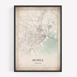 May include: Framed map print of Mobile, Alabama, featuring a detailed street and waterway layout. The map has a vintage aesthetic with a beige background and a black frame. The city name and coordinates are printed at the bottom.