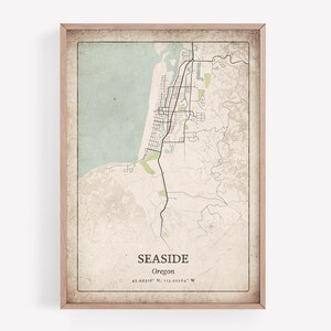 Może przedstawiać: Oprawiony wydruk mapy Seaside w stanie Oregon, przedstawiający szczegółowy układ ulic i otaczającą topografię. Mapa ma styl vintage z jasnym zielonym i beżowym schematem kolorów i zawiera nazwę miasta i współrzędne.