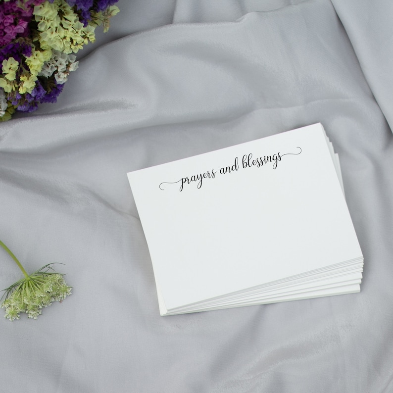 May include: A stack of white note cards with the text "prayers and blessings" in black cursive script.