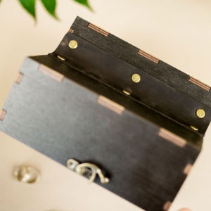 May include: A black wooden box with a hinged lid and a brass latch. The box is lined with black fabric and has brass rivets along the edge.