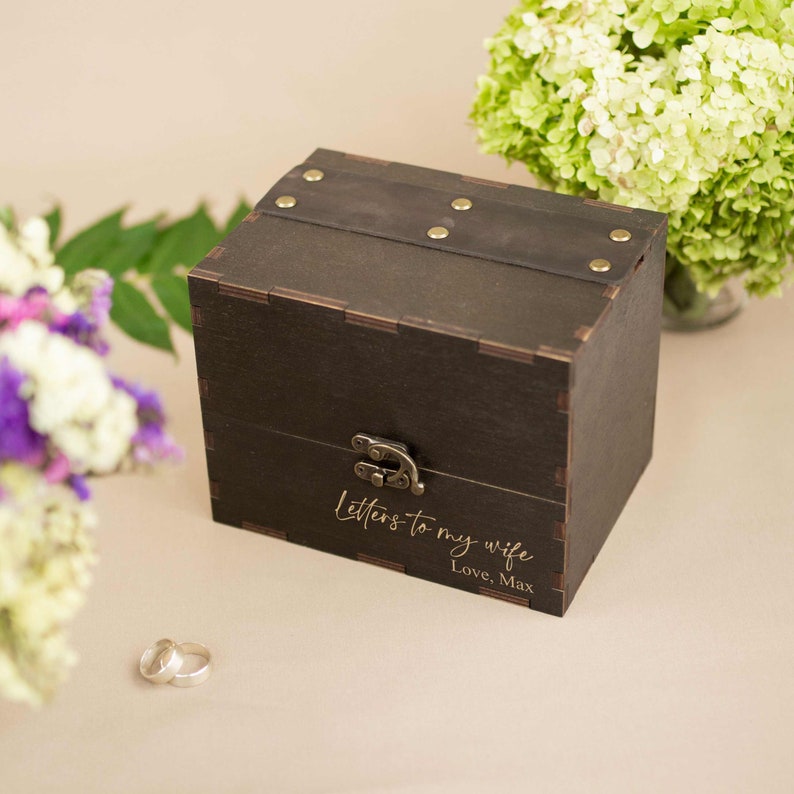 May include: A dark brown wooden box with a hinged lid and a brass latch. The box is engraved with the text "Letters to my wife, Love, Max".