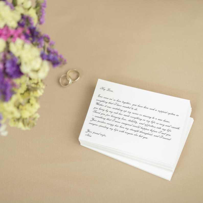 May include: A white card with black cursive writing on it. The card reads "Hey Love, Ever since we've been together, you have been such a support system in everything that I have wanted to do. Whether it was switching up my rover or moving to a new home, you being by my side has made everything in my life so easy and smooth. Thank you for bringing love, stability, and affection into my life - something that I never imagined would happen before I met you. Your positive energy has been my strength throughout, and I cannot imagine spending my life with anyone else but you. Your proud wife, Neva."