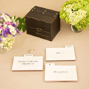May include: A wooden box with a hinged lid and a brass latch. The box is labeled "Letters to my husband" and "Love, Nina". The box is surrounded by three wooden cards with handwritten messages. The cards are labeled "Adventures", "Secrets", and "Shhh...!".