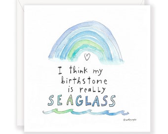 May include: A watercolor illustration of a rainbow with a heart at the top. The text below reads "I think my birthstone is really SEAGLASS" with waves drawn underneath. The artist's signature is in the bottom right corner.