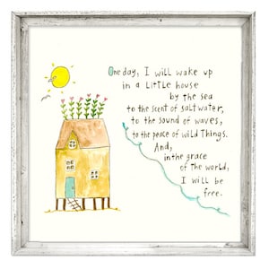 May include: Watercolor art print in a white wooden frame. The artwork features a yellow house with a green door and a rooftop garden. The text reads, "One day, I will wake up in a Little house by the sea... I will be free."