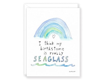 May include: A watercolor illustration of a rainbow with a heart at the top. The text below reads "I think my birthstone is really SEAGLASS".