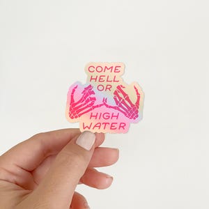 May include: A holographic sticker with pink and orange hues featuring two skeleton hands making a pinky promise with the text "Come Hell or High Water" in red.