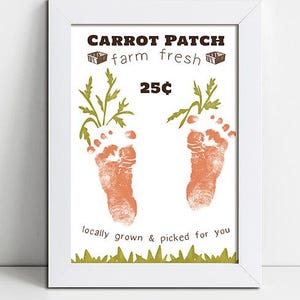 May include: Framed print with the words "Carrot Patch farm fresh" and the price "25p". The print features two orange baby footprints with green carrot tops and the text "locally grown & picked for you".